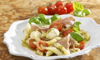 Tomato pasta salad with mozzarella, ham and pesto