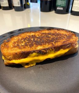 cheese toasty with a toasted top and bottom on a black plate. The cheese shown melted in-between the toasted bread