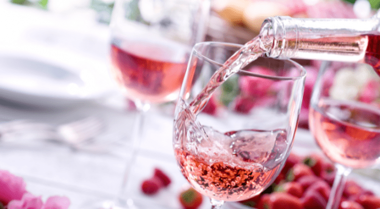Sparkling red wine being poured into a wine glass on a picnic table