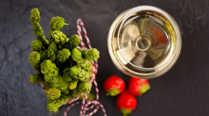 Grüner Spargel mit Weißwein und Erdbeeren auf Schiefer, Topshot.