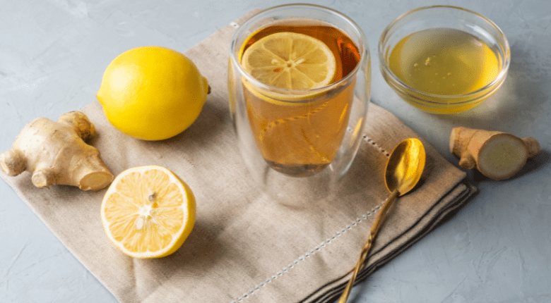 Ein Glas mit Ingwertee, garniert mit Zitronen.