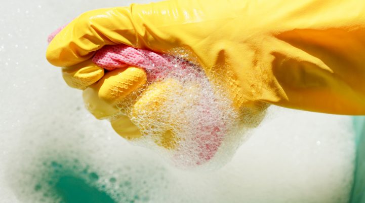 hand in gummihandschuh gelbes ringt aus nassen staubtuch